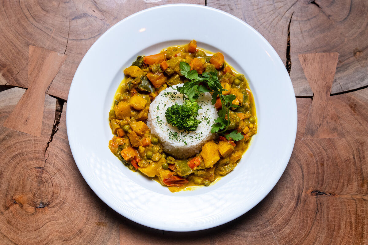 Vegetable curry with a rice dome, shot from above on a wooden table