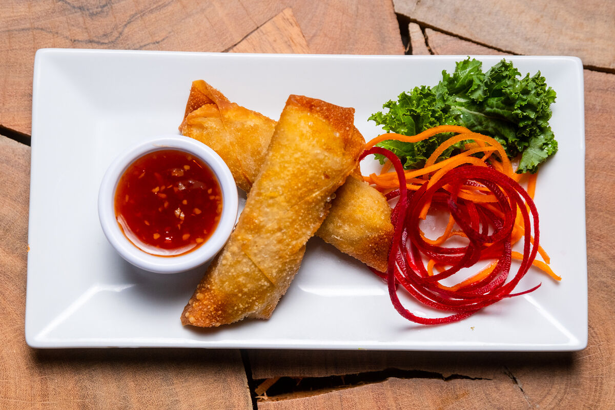 Spring rolls with sweet chili sauce and beet curls on a square plate