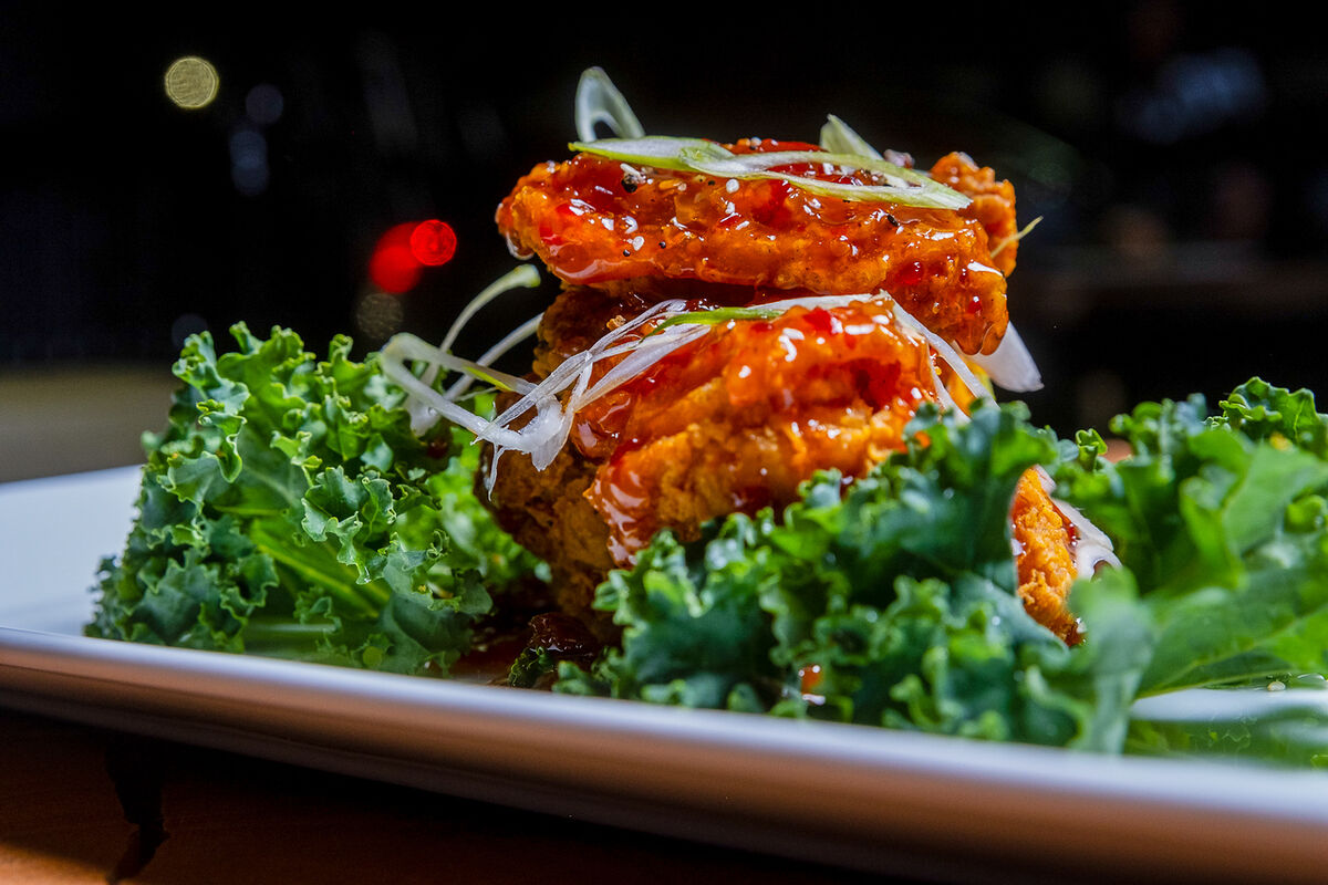 Glazed wings on a bed of kale, shot low with the dining room behind
